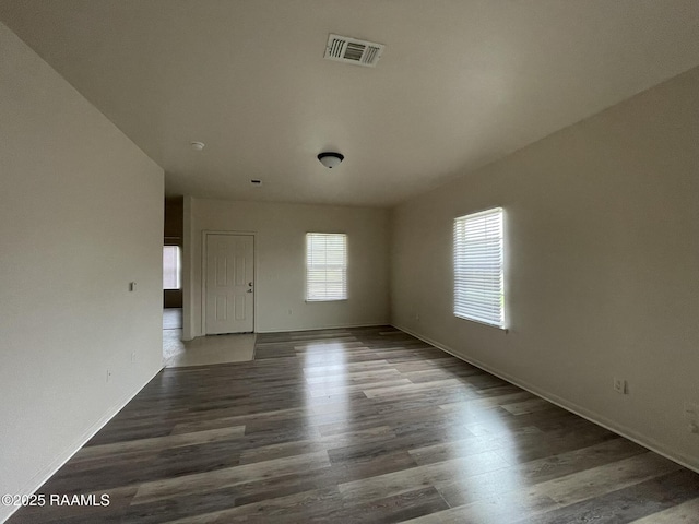 spare room with baseboards, wood finished floors, and visible vents