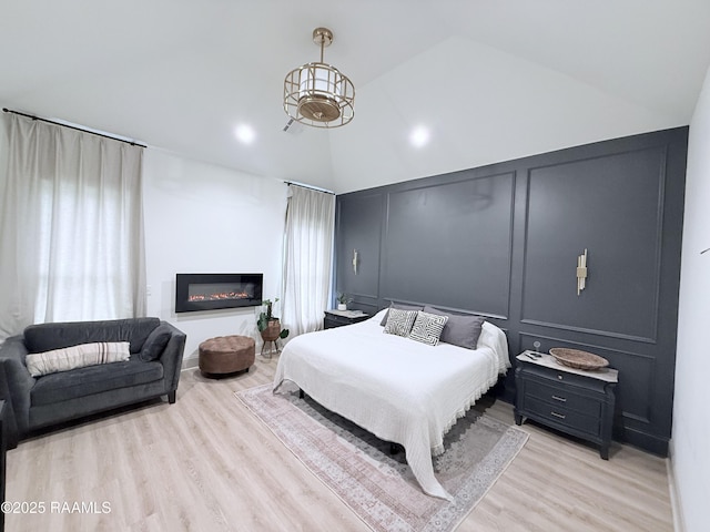 104 Cherrywood Dr, Lafayette, LA 70508 - bedroom with a decorative wall, lofted ceiling, light wood-style floors, and a glass covered fireplace