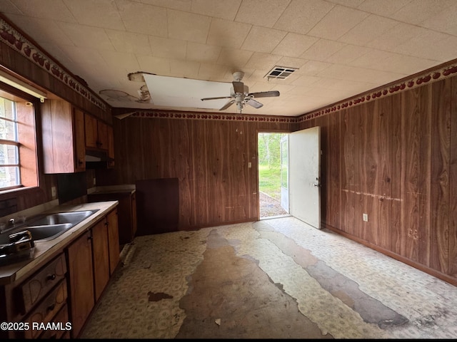 kitchen featuring visible vents, wood walls, a sink, and ceiling fan