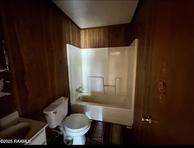 bathroom featuring shower / washtub combination, wood walls, toilet, and vanity