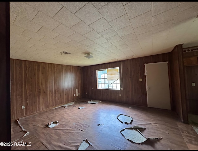 spare room featuring wooden walls and visible vents