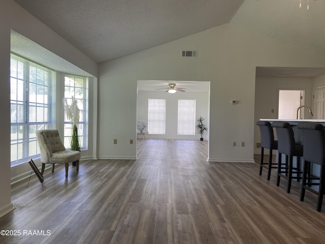 living room with visible vents, dark wood-style flooring, a healthy amount of sunlight, and high vaulted ceiling