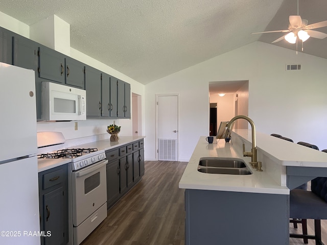 kitchen with visible vents, vaulted ceiling, a sink, light countertops, and white appliances