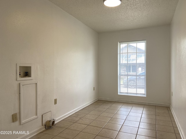 interior space with laundry area, baseboards, hookup for a washing machine, a textured ceiling, and light tile patterned floors