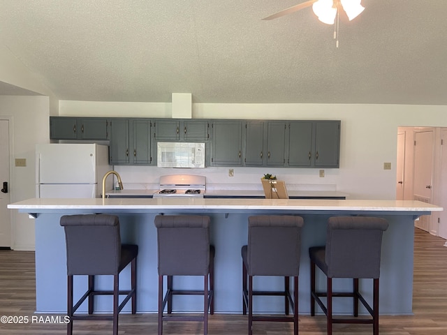 kitchen featuring white appliances, a kitchen breakfast bar, and light countertops