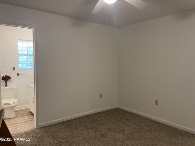 carpeted empty room featuring a ceiling fan and baseboards