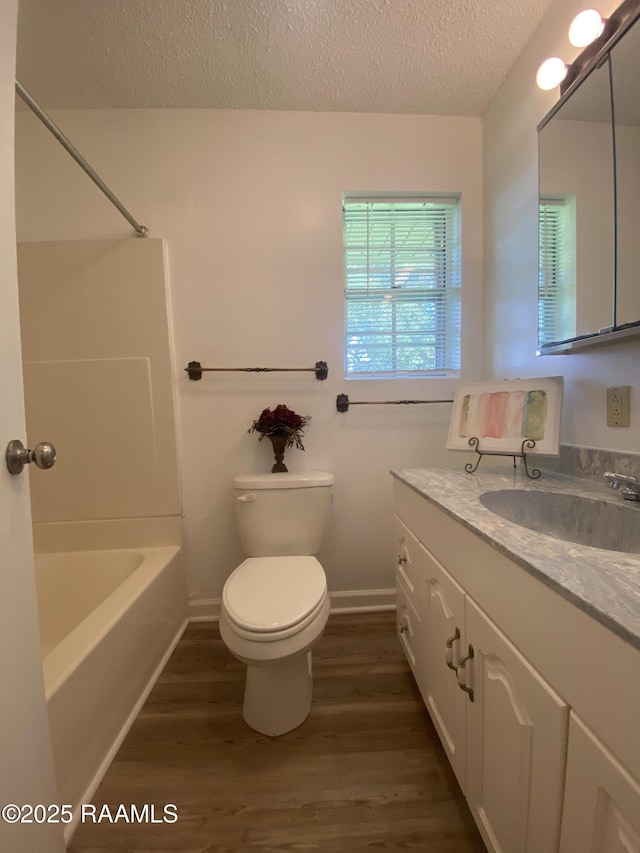 bathroom with vanity, wood finished floors, toilet, a textured ceiling, and shower / bath combination
