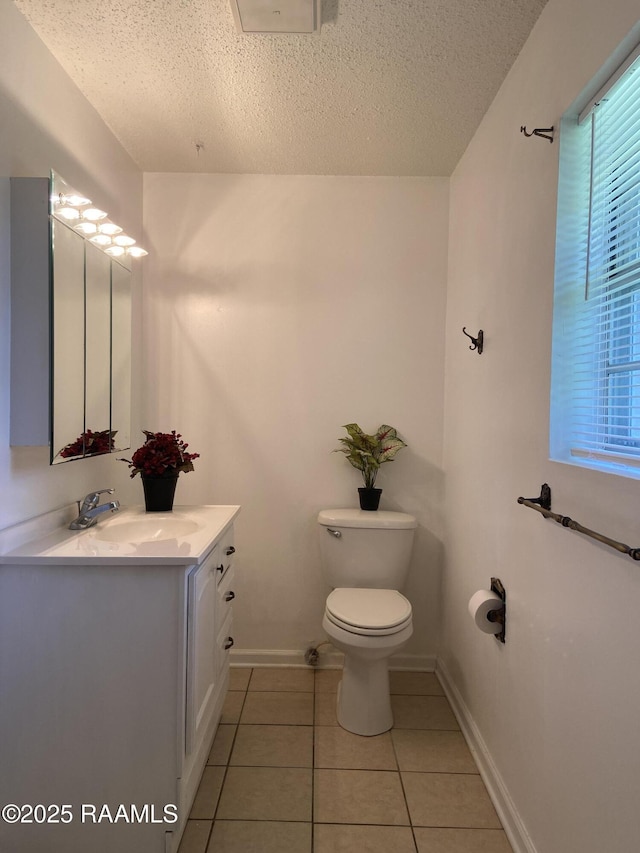 bathroom with a textured ceiling, tile patterned flooring, vanity, baseboards, and toilet