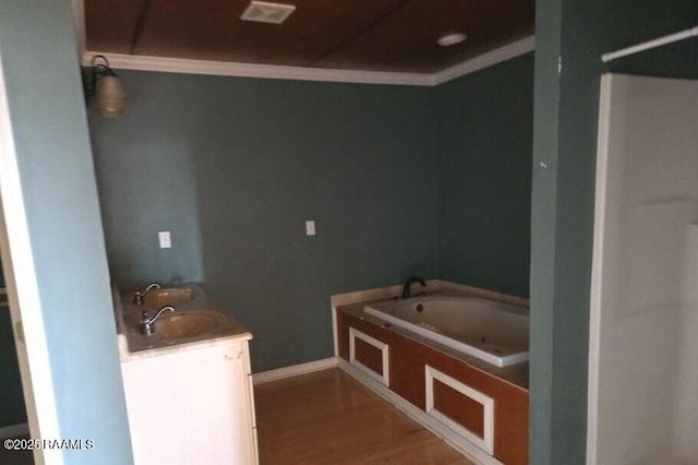 bathroom with crown molding, vanity, baseboards, wood finished floors, and a garden tub