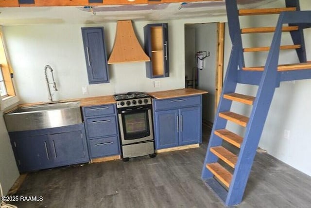 kitchen featuring custom exhaust hood, dark wood-style floors, stainless steel range with gas stovetop, a sink, and blue cabinetry