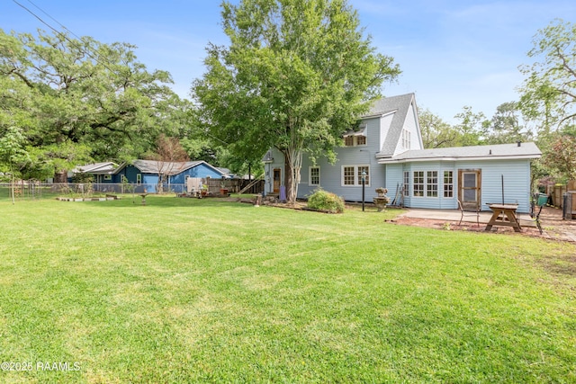 rear view of property featuring a patio, fence, and a lawn