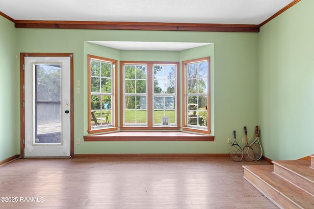 interior space with stairway, wood finished floors, ornamental molding, and baseboards