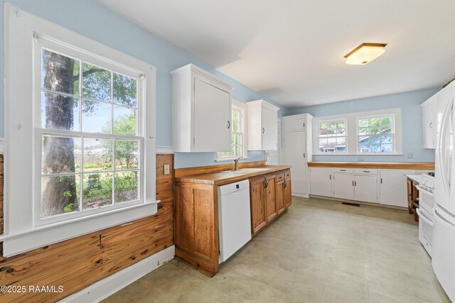 kitchen featuring a sink, white dishwasher, visible vents, light countertops, and white cabinets