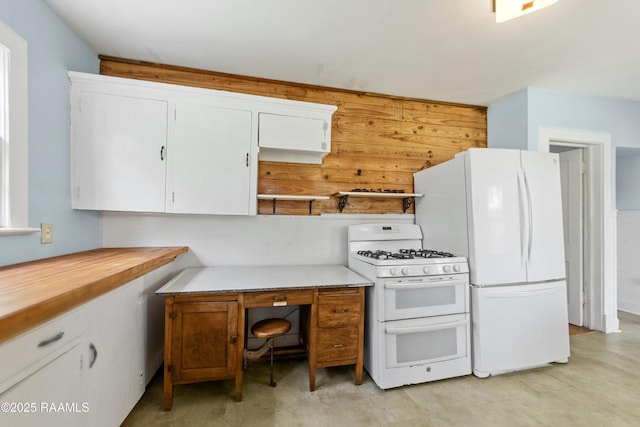 kitchen with white cabinets, white appliances, and wood walls