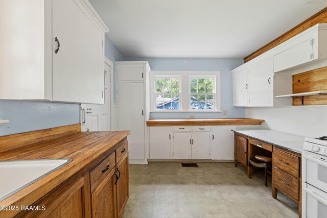 kitchen featuring built in desk, white range with gas cooktop, open shelves, white cabinets, and butcher block counters