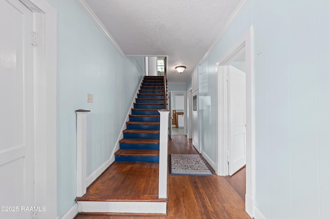 stairs featuring baseboards, wood finished floors, and crown molding