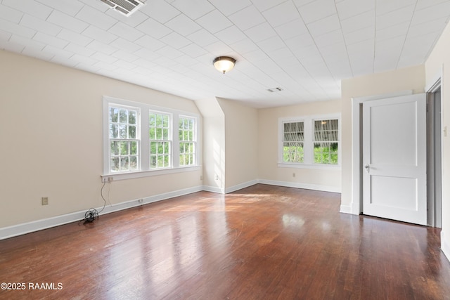 spare room featuring visible vents, baseboards, wood finished floors, and plenty of natural light