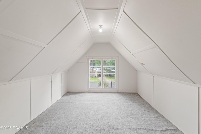 bonus room with vaulted ceiling and light colored carpet