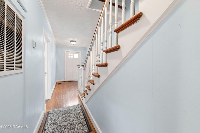 entryway with a heating unit, crown molding, stairs, baseboards, and wood finished floors