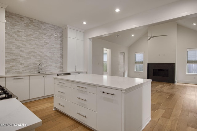 102 Drifting Sands Ln, Lafayette, LA 70503 - kitchen with light wood finished floors, a sink, tasteful backsplash, a kitchen island, and light countertops