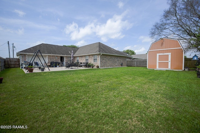 rear view of house featuring a patio, a storage unit, a fenced backyard, and a yard
