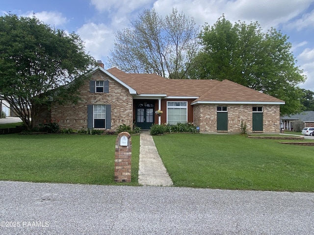view of front of property with a chimney, a front yard, and brick siding