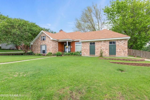 single story home featuring fence, a chimney, a front yard, and brick siding