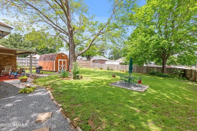 view of yard featuring an outbuilding, a patio, a storage unit, and a fenced backyard