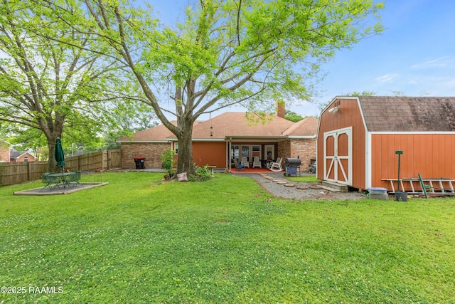 back of house with an outdoor structure, a yard, a storage unit, fence, and a patio