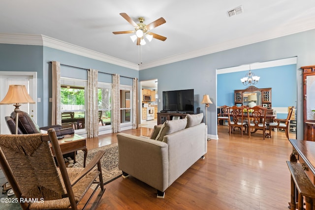 living area featuring wood finished floors, visible vents, crown molding, and ceiling fan with notable chandelier