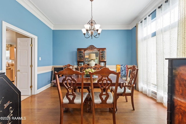 dining area with wood finished floors, a chandelier, and ornamental molding