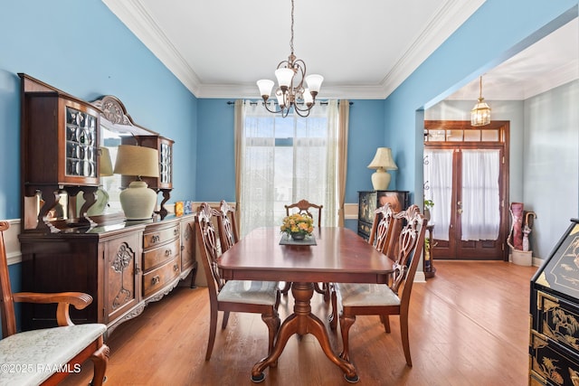 dining space featuring ornamental molding, an inviting chandelier, and light wood-style floors