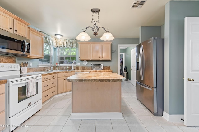kitchen with light brown cabinetry, visible vents, stainless steel appliances, and light countertops