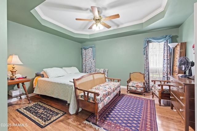 bedroom with wood finished floors, crown molding, and a tray ceiling
