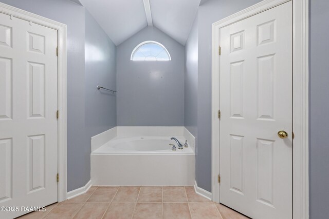 bathroom with tile patterned flooring, a bath, vaulted ceiling, and baseboards