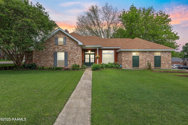 view of front of house featuring a lawn and brick siding