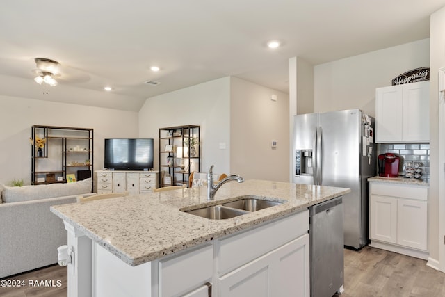 kitchen with light wood-style floors, stainless steel appliances, open floor plan, and a sink