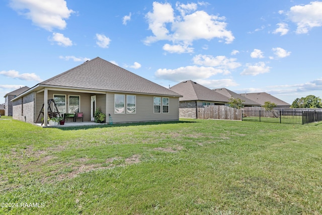 back of property with a patio, fence, a yard, and roof with shingles