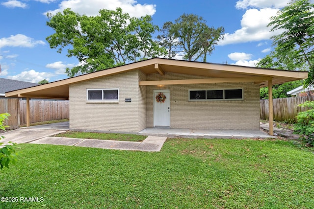 view of front of home featuring fence, a carport, a front yard, and brick siding