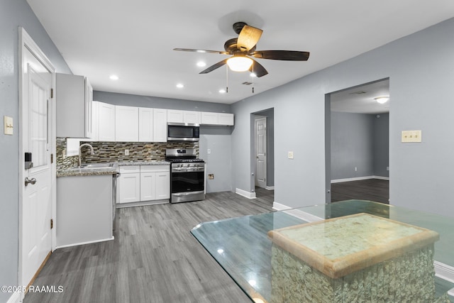 kitchen with appliances with stainless steel finishes, a sink, light wood-style floors, a ceiling fan, and white cabinetry