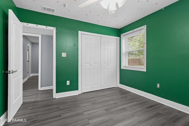 unfurnished bedroom featuring a closet, wood finished floors, and visible vents