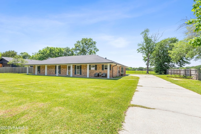 single story home with a front lawn, brick siding, concrete driveway, and fence