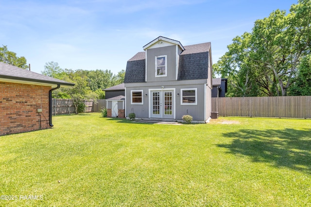 back of property featuring french doors, a fenced backyard, a yard, and roof with shingles