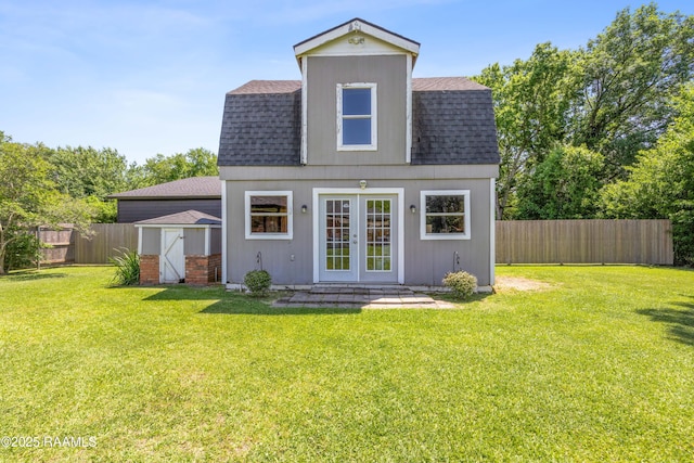 back of house featuring french doors, a fenced backyard, a shingled roof, and an outdoor structure