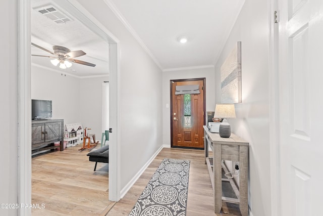 foyer entrance with crown molding, light wood finished floors, a ceiling fan, and visible vents