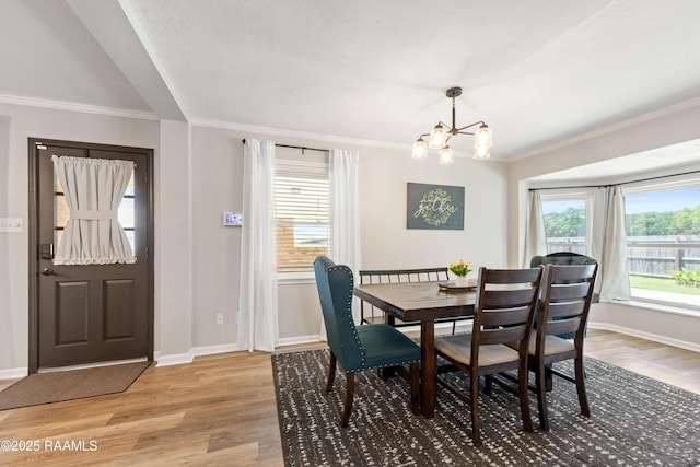 dining area with an inviting chandelier, light wood-style floors, and ornamental molding