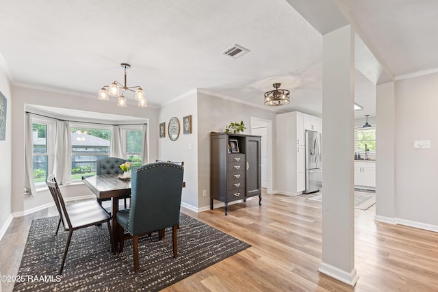 dining area featuring a chandelier, ornamental molding, light wood-type flooring, baseboards, and visible vents
