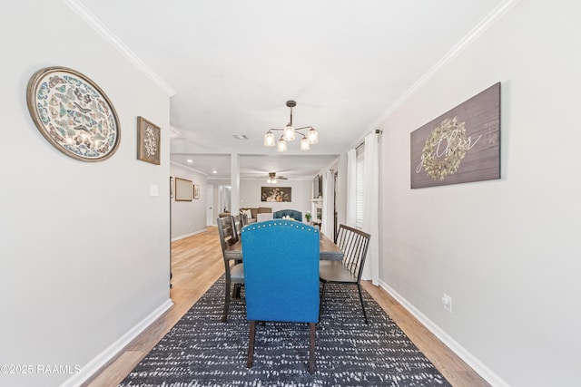 dining space featuring a chandelier, baseboards, crown molding, and light wood finished floors