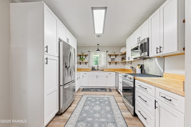 kitchen with open shelves, a sink, visible vents, wooden counters, and stainless steel appliances