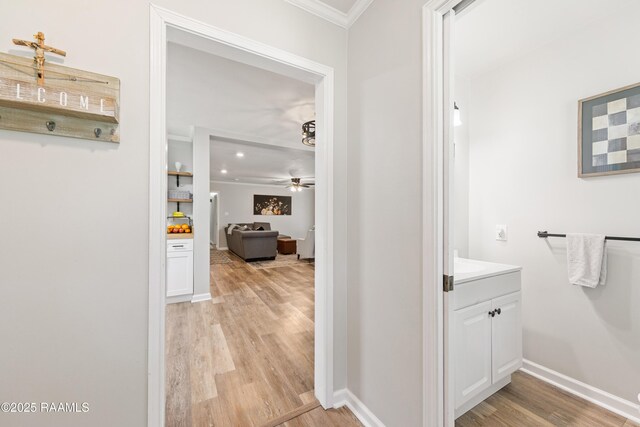 corridor with baseboards, light wood-style flooring, and crown molding